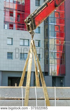 Concrete Curbs Are Lifted By A Mobile Crane Against The Backdrop Of A Modern Building
