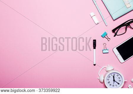 Phone, Notebook, Alarm Clock, Paper Clips, Pen, Marker And Glasses Lie On A Pink Background. Copy Sp