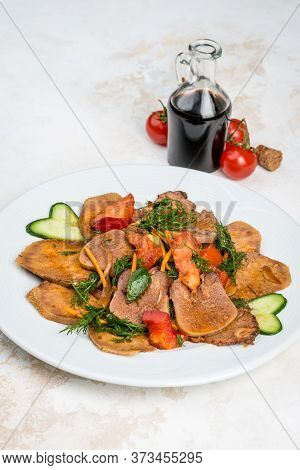 Beef Tongue With Sauce And Vegetables On A White Plate