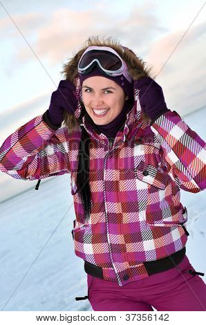 Sorridendo la giovane donna che indossa tuta sci in posa all'aperto in inverno
