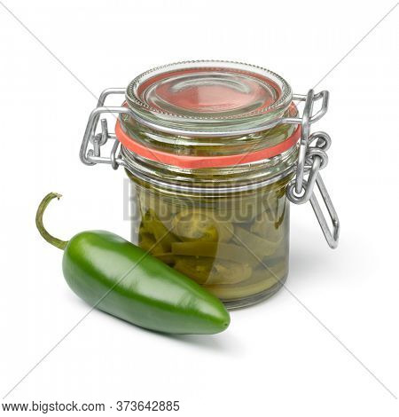 Glass jar with pickled green jalapeno pepper slices and a fresh pepper in front isolated on white background