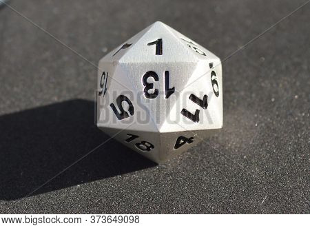 Silver Metallic D20 Twenty Sided Dice On Foam Surface In Bright Sunshine