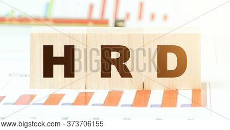 Black Letters Hrd On Wooden Blocks On Table With Different Color Graphs And Schemas In Brightly Lit 