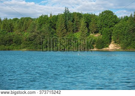 Tranquil View To Bright Forest Near Steep Shore Of Mountain Lake. Coniferous Trees On Steep Slope.