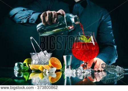 Barman is making campari orange cocktail at night club