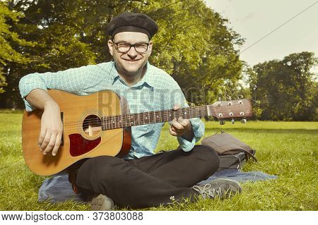 Funny Man On City Park Summer Meadow Enjoying Day With Guitar