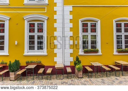Husum, Germany - June 27, 2019: Benches In Front Of A Yellow Restaurant In Husum, Germany