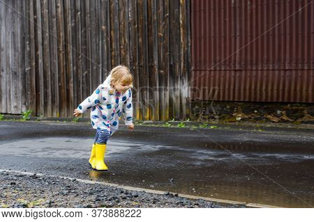 Little Toddler Girl Wearing Yellow Rain Boots, Running And Walking During Sleet On Rainy Cloudy Day.
