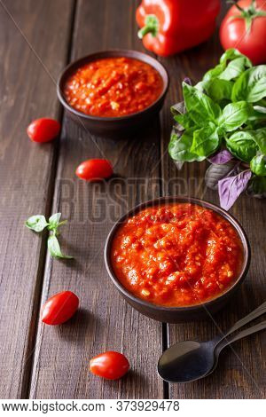 Balkan Sauce Ajvar In A Clay Bowl And Ingredients For Its Preparation On A Wooden Background. Serbia
