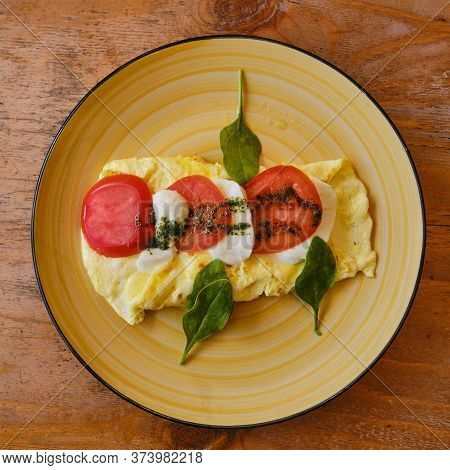 Breakfast On A Round Yellow Plate. Omelet And Ingredients Of Italian Caprese Salad. Cliced Fresh Moz