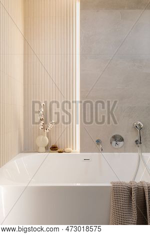 Modern Bright Bathroom With Lamella Wall. Big White Bath With Silver Faucet And Brown Towel.