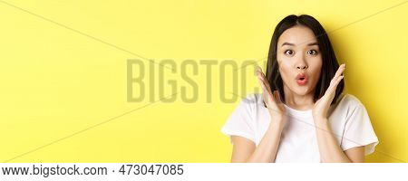 Close Up Of Surprised Asian Girl Say Wow, Stare At Camera Amzed With Hands Near Face, Standing Over 