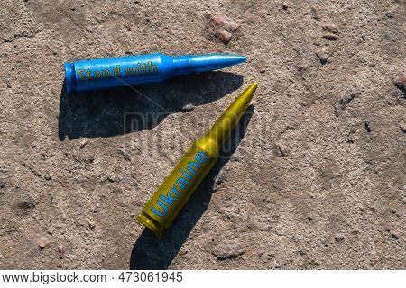 Yellow And Blue Rifle Cartridges With The Inscription Stand With Ukraine Lie On A Concrete Surface (