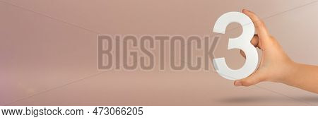 Number Three In Hand. Hand Holding White Number 3 On Red Background With Copy Space. Concept With Nu
