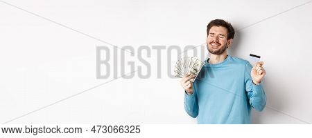 Cheerful Guy Celebrating Salary, Dancing With Plastic Credit Card And Money, Smiling Satisfied, Stan