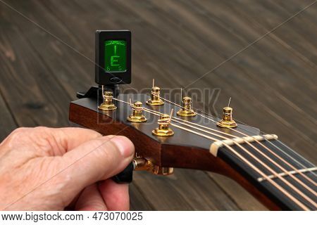 Hand Tuning A Guitar With A Tuner. Close Up.