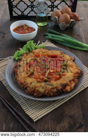 Eggs Cooked With Vegetables And Peas On Wooden Table