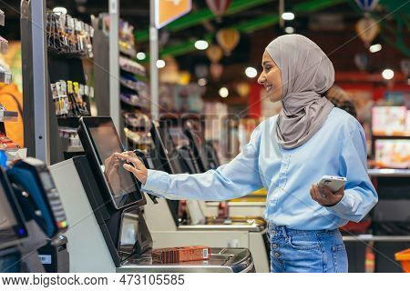 A Woman Buyer In A Supermarket In A Hijab Pays For Goods At A Self-service Checkout, Convenient Serv