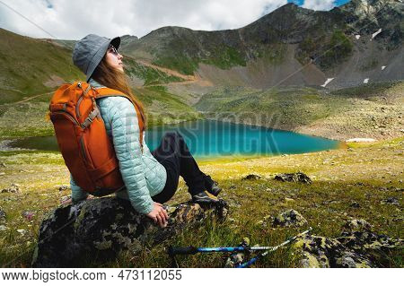A Woman Sits In A Vantage Point Above A Stunning Turquoise Lake Surrounded By Mountains During The D