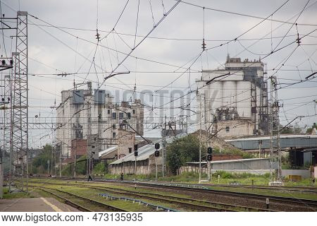 A View Of A Train Station From A Distance. Railroads Empty, People Cross Rails