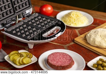 Cooking Pizza Waffle, Piffle. Different Ingredients - Sausage, Olives, Pickles, Dough On The Kitchen