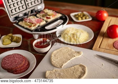 Cooking Waffles Stuffed With Sausage, Cheese. Pizza Waffle, Piffle. Various Ingredients On The Kitch