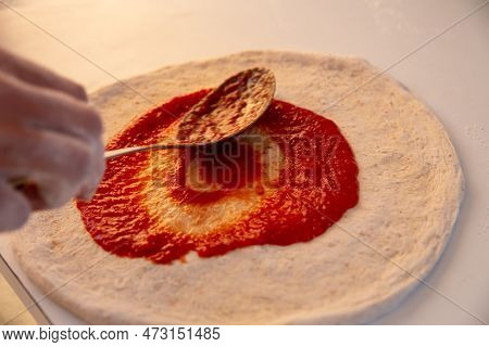 Spreading Marinara On A Pizza Before Adding Cheese