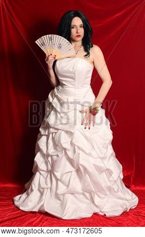 Woman Wearing Satin Corset Style Ball Gown Wedding Dress On Red Velvet Background
