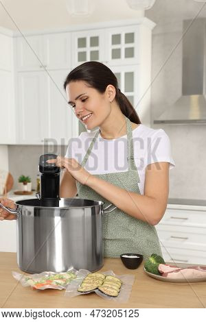 Woman Using Thermal Immersion Circulator At Table In Kitchen. Sous Vide Cooking