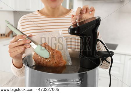 Woman Putting Vacuum Packed Meat Into Pot And Using Thermal Immersion Circulator, Closeup. Sous Vide