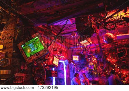 Interior Of Szimpla Kert, Famous Ruin Pub In Budapest At Night. Old Computer Screens On The Walls. N