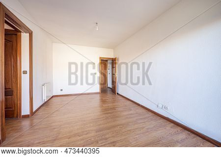 Empty Living Room With Floating Oak Flooring, Access Doors To Other Rooms In Varnished Sapele, White