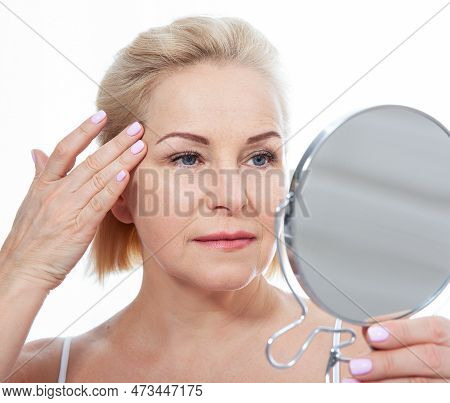 Happy Middle Aged Woman Model Touching Face Skin Looking In Mirror. Smiling Mature Older Lady Enjoyi