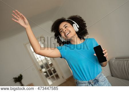 Happy Young Curly Black Woman In Wireless Headphones Listen Music, Enjoy Spare Time, Danse, Has Fun