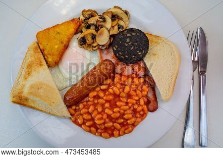 White Board With Full English Breakfast With Bacon, Fried Egg, Beans, Tomato, Roasted Sausage, Black