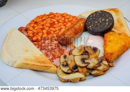 White Board With Full English Breakfast With Bacon, Fried Egg, Beans, Tomato, Roasted Sausage, Black