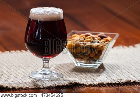 Glass Of Belgian Abbey Red Brown Beer And Glass Bowl With Party Nuts