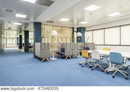 A Coworking Office With A Boardroom Table And Meeting Booths, Wooden Latticework And Blue Carpeted F