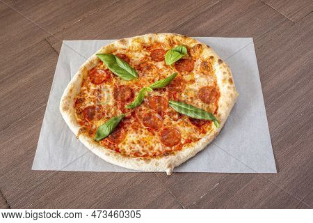 Spicy Pepperoni Italian Pizza Topped With Basil Leaves On Greaseproof Paper