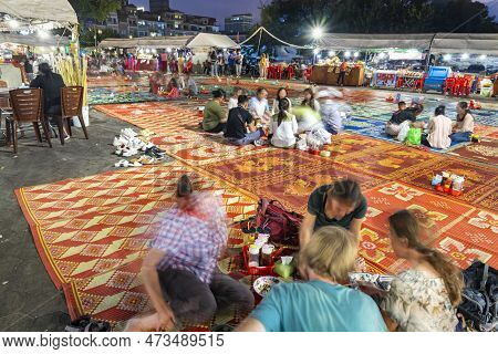 Phnom Penh,cambodia-december 23rd 2022:as Dusk Falls,khmer And Western Travelers Sit In Small Groups