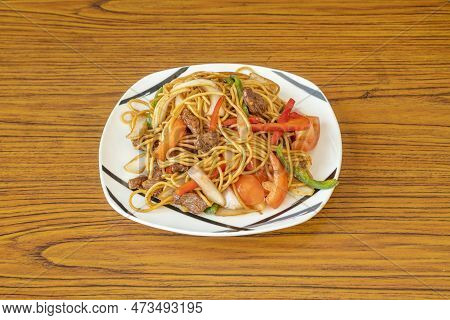 Peruvian Recipe Of Sautéed Noodles With Beef Tenderloin, Diced Tomatoes And Onion, Strips Of Red And