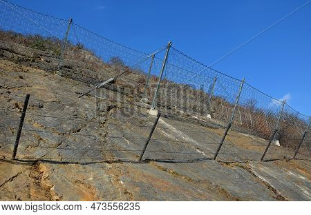 Reinforcing Slope With A Steel Net Anchored Deep Into Rock. Rows Inclined Fences With Massive Nettin