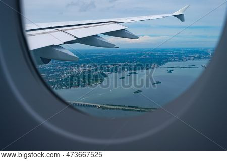 View From Porthole. Aircraft Window Or Porthole. Aircraft Wing Seen Through Porthole. Plane Porthole