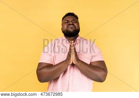 Portrait Of Unhappy Man Wearing Pink Shirt Looking Up With Beseeching Imploring Expression, Praying 