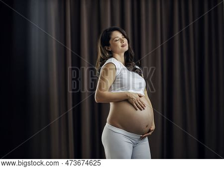 Portrait Of A Happy Pregnant Woman Touching Her Tummy Full Of Stretchmarks.