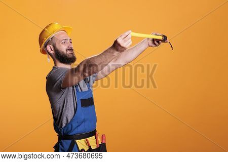 Confident Construction Worker Using Tape Measure To Take Measurements And Work On Refurbishment Proj