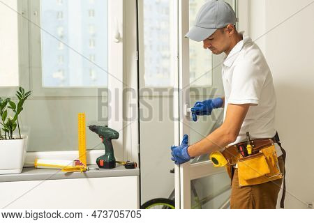 A Repairman Repairs, Adjusts Or Installs Metal-plastic Windows In The Apartment. Glazing Of Balconie