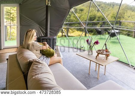 Transparent Bubble Tent At Glamping, Lush Forest Around And Interior. Woman Resting In Glamping