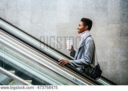 Side View Of Stylish African American Female In Stylish Coat And Sweater. She Is With Cup Of Coffee 