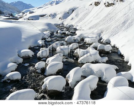 Neve-caped pietre nel fiume